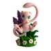 A small pink cartoon creature with large blue eyes sits among green grass, white flowers, and purple plants against a patterned background—perfect for fans of The Pokémon Company’s Pokémon TCG: 30th Celebration Figure Collection or as a display piece alongside your favorite collectibles.